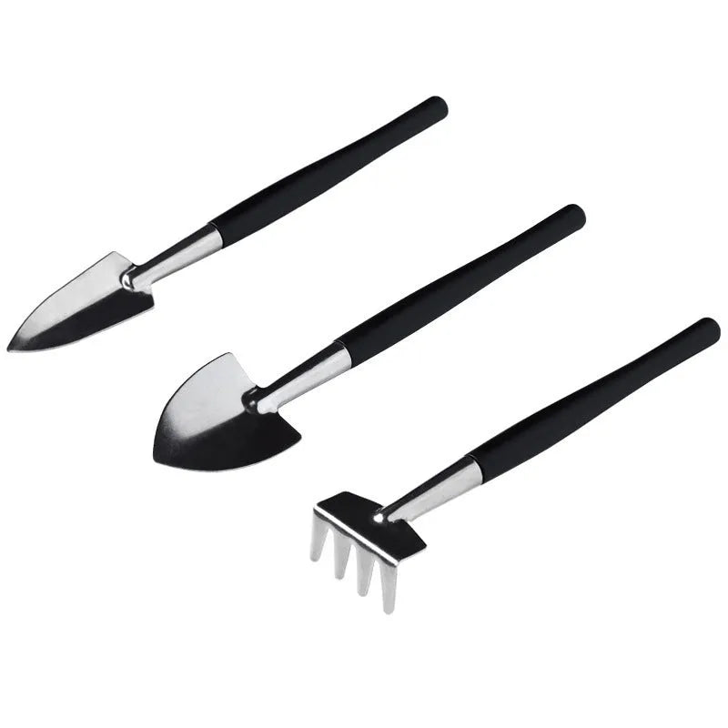 Black mini garden hand tools set including scissors, tweezers, shovels and spray bottle arranged on a cushion for succulent care