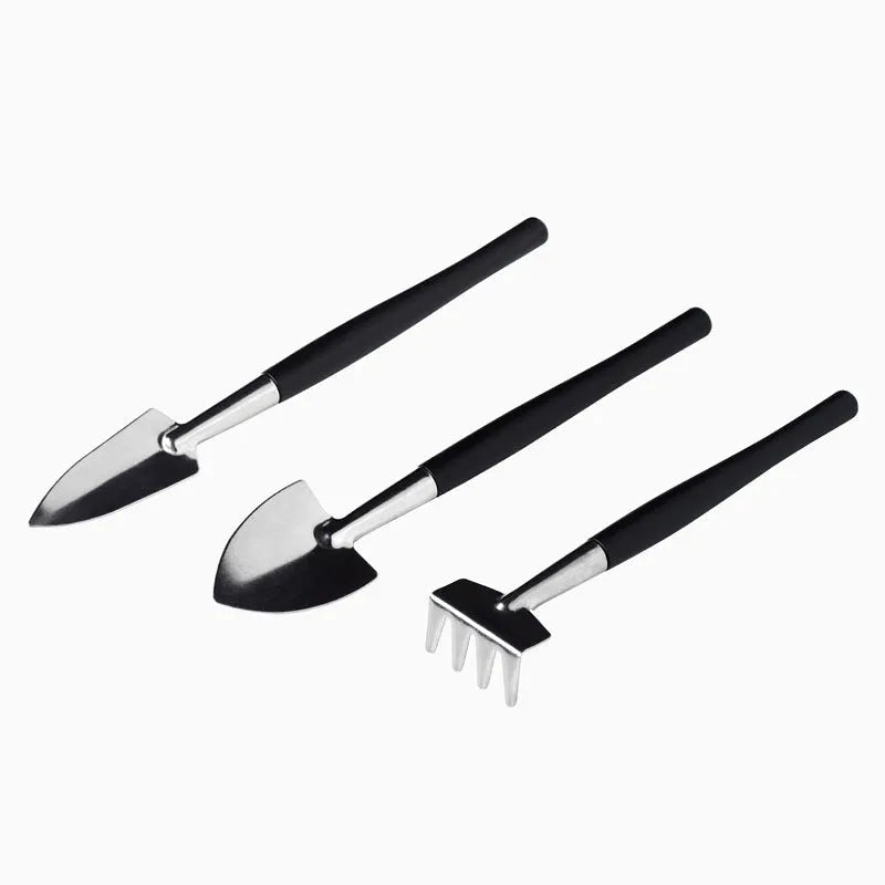 Black mini garden hand tools set including scissors, tweezers, shovels and spray bottle arranged on a cushion for succulent care