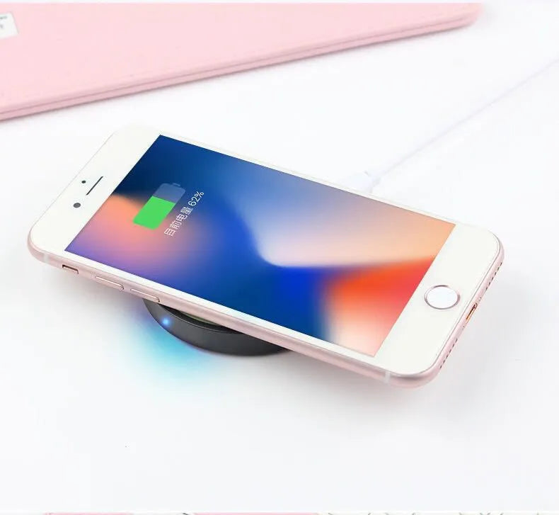 Square 69mm wireless charging pad in a choice of six colours on a desk next to a mobile phone.