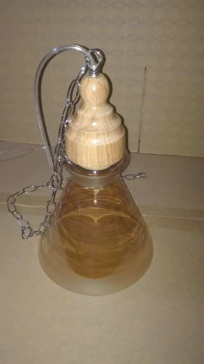 Glass single head pendant light with wood grain finish and adjustable cable, shown in a Nordic style interior.