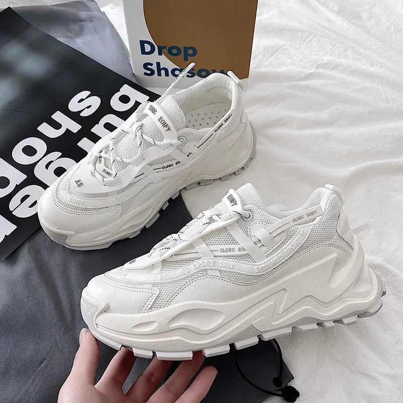 White and black chunky trainers with breathable mesh upper, thick rubber sole, front laces, and round toe