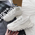White and black chunky trainers with breathable mesh upper, thick rubber sole, front laces, and round toe