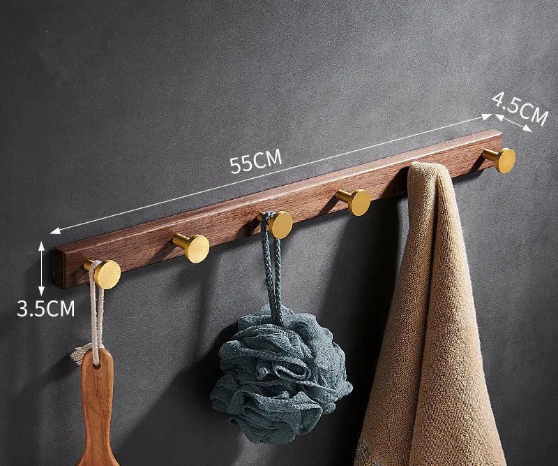 A row of black walnut aluminium wall hooks with a brass wire drawing finish, shown in a bathroom setting.