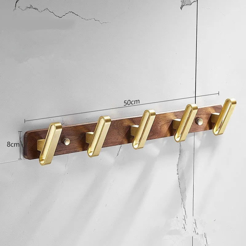 A row of black walnut aluminium wall hooks with a brass wire drawing finish, shown in a bathroom setting.