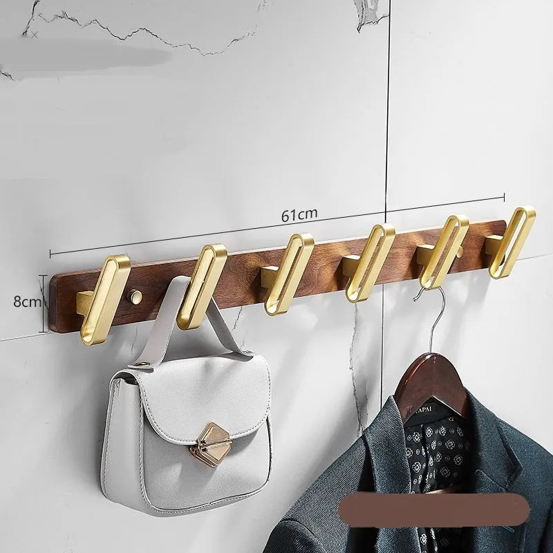 A row of black walnut aluminium wall hooks with a brass wire drawing finish, shown in a bathroom setting.