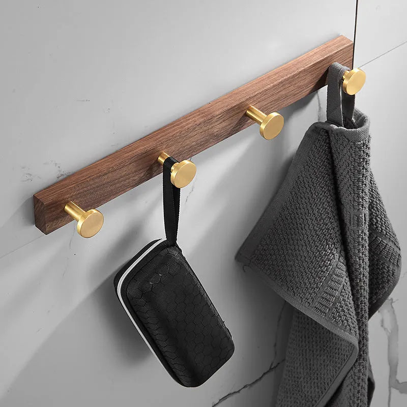 A row of black walnut aluminium wall hooks with a brass wire drawing finish, shown in a bathroom setting.
