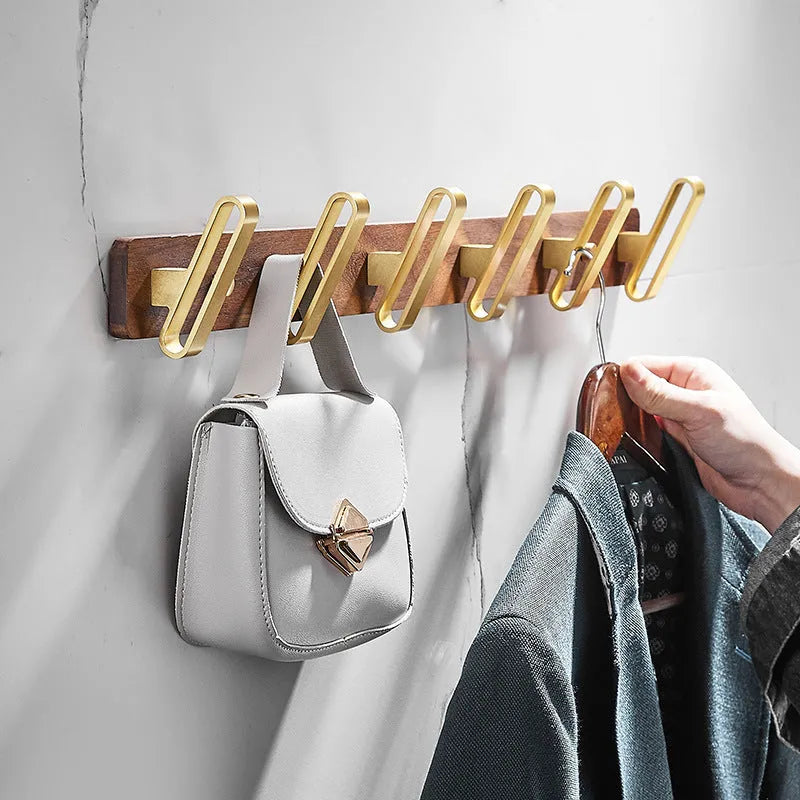A row of black walnut aluminium wall hooks with a brass wire drawing finish, shown in a bathroom setting.