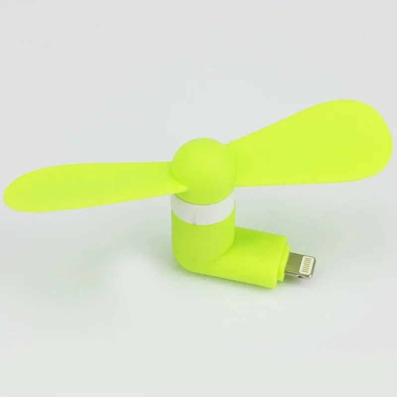Portable white mini fan with plastic blades connected to a smartphone showing rotary switch.