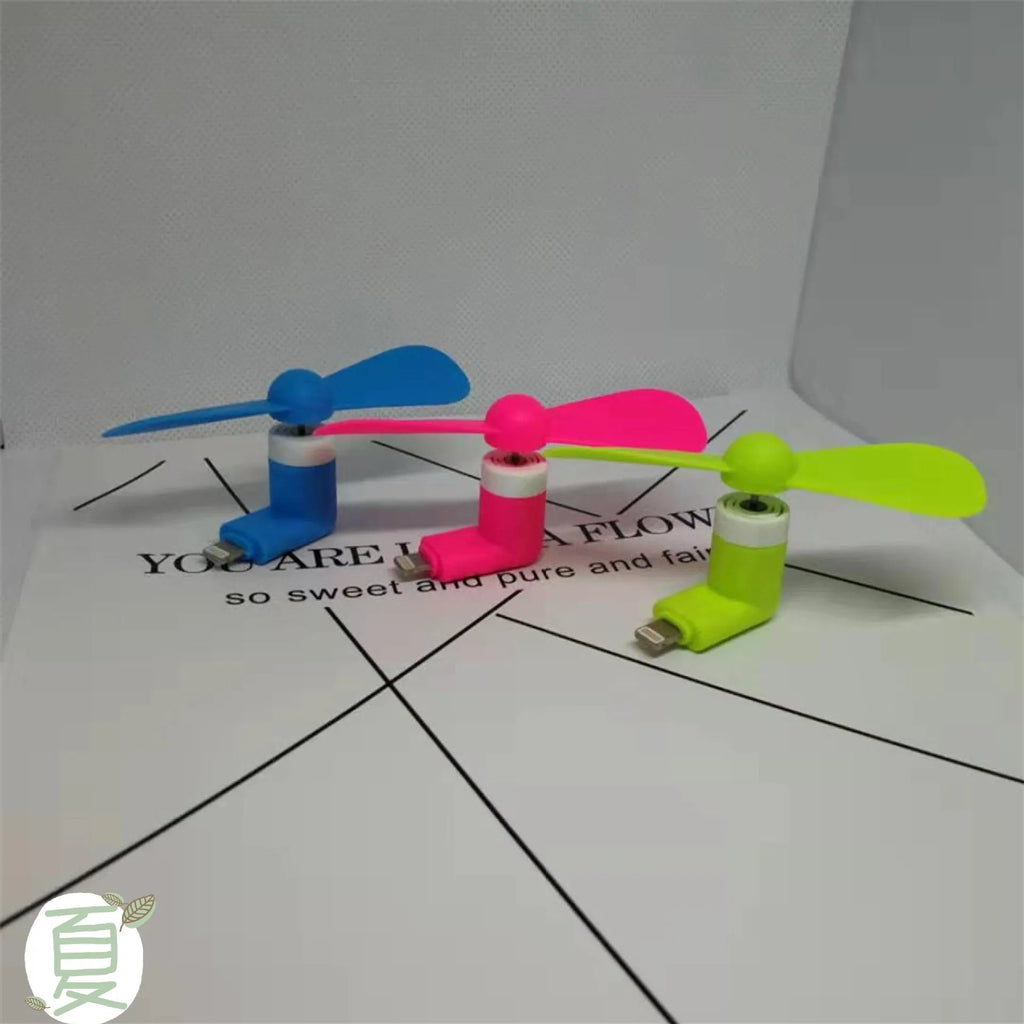 Portable white mini fan with plastic blades connected to a smartphone showing rotary switch.