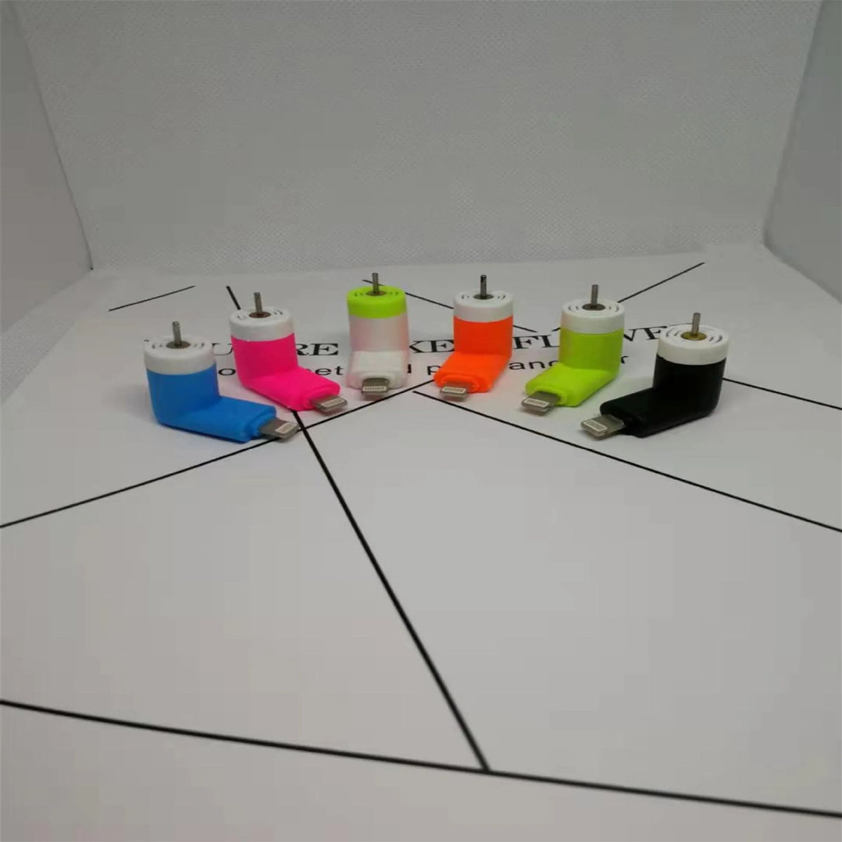 Portable white mini fan with plastic blades connected to a smartphone showing rotary switch.