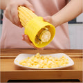 Yellow manual corn grinder thresher kitchen tool with corn-shaped design on a white background.