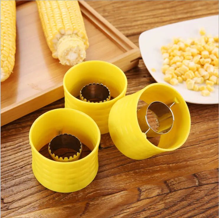 Yellow manual corn grinder thresher kitchen tool with corn-shaped design on a white background.