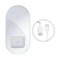 Baseus black wireless charger charging iPhone and AirPods simultaneously on wooden desk