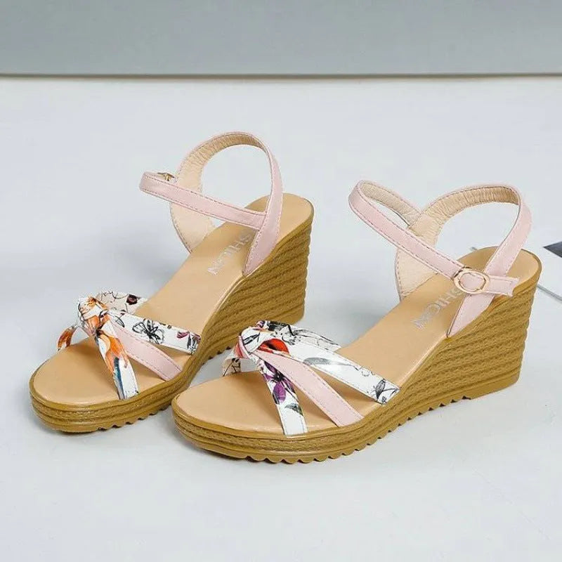 Pink and white women's wedge sandals with a thick heel and buckle strap.
