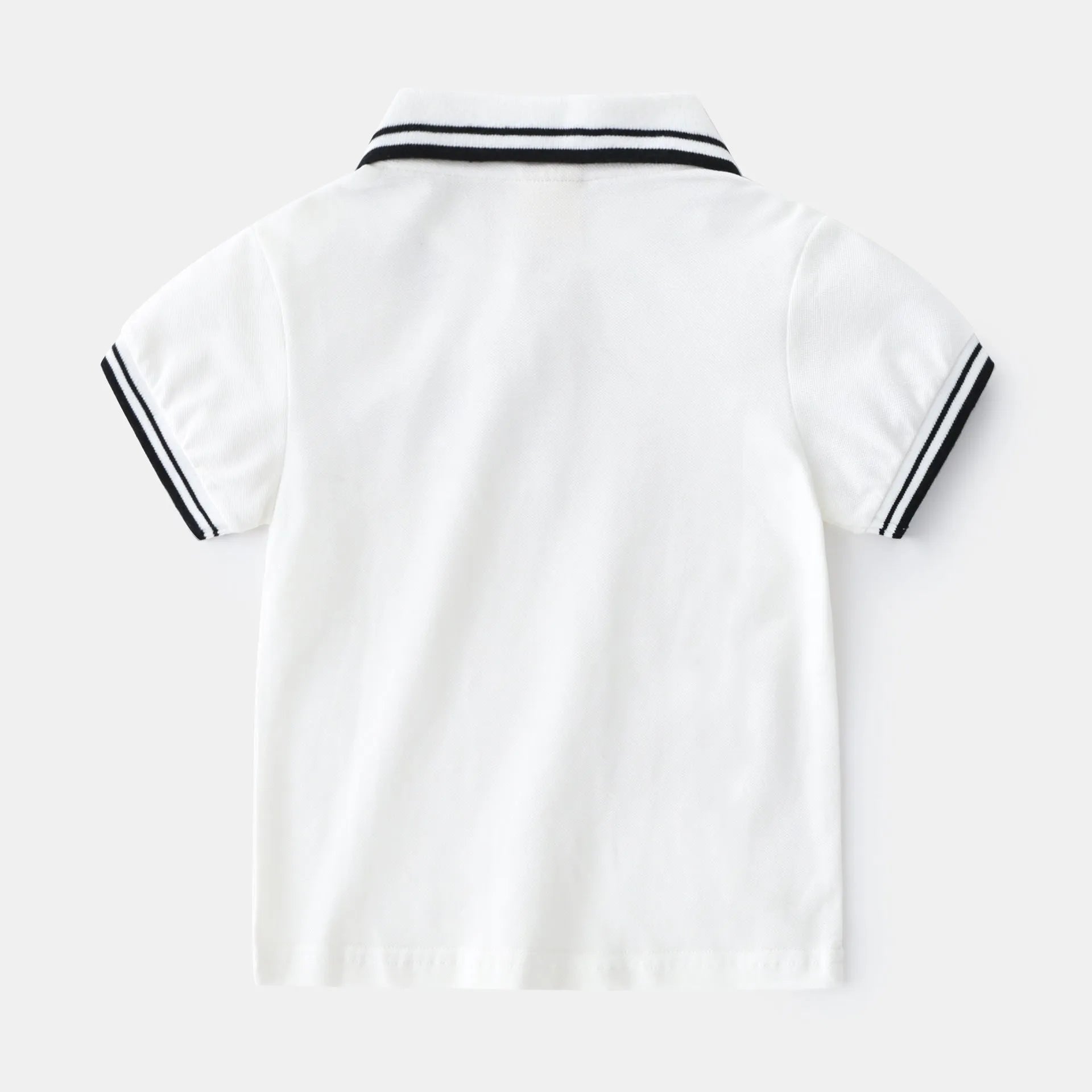 White and black boys' short sleeve cotton polo shirt laid flat.