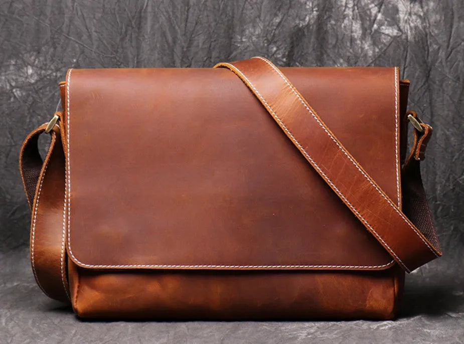 Vintage brown leather men's messenger bag with shoulder strap showing internal organiser pockets.