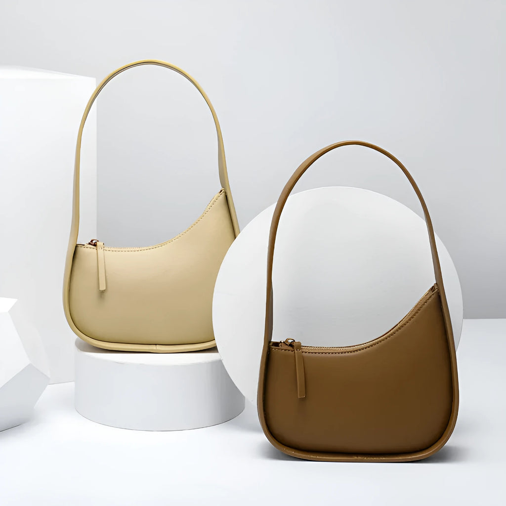 Small half-moon shaped leather ladies handbag with wide shoulder strap and zip opening