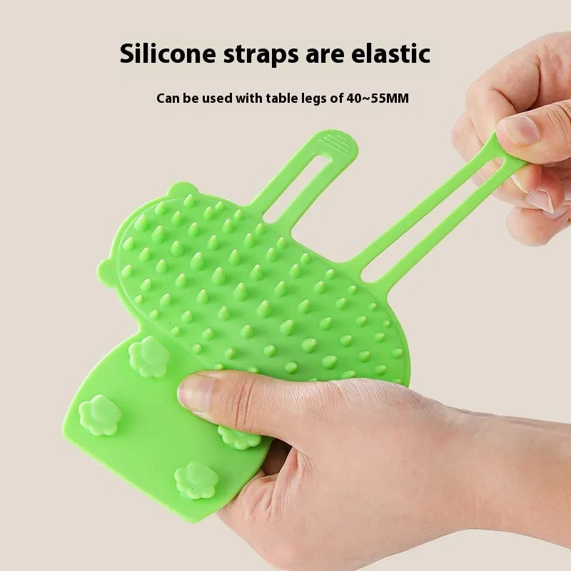 Adjustable silicone cat scratching grooming brush in black, mounted on a table leg.