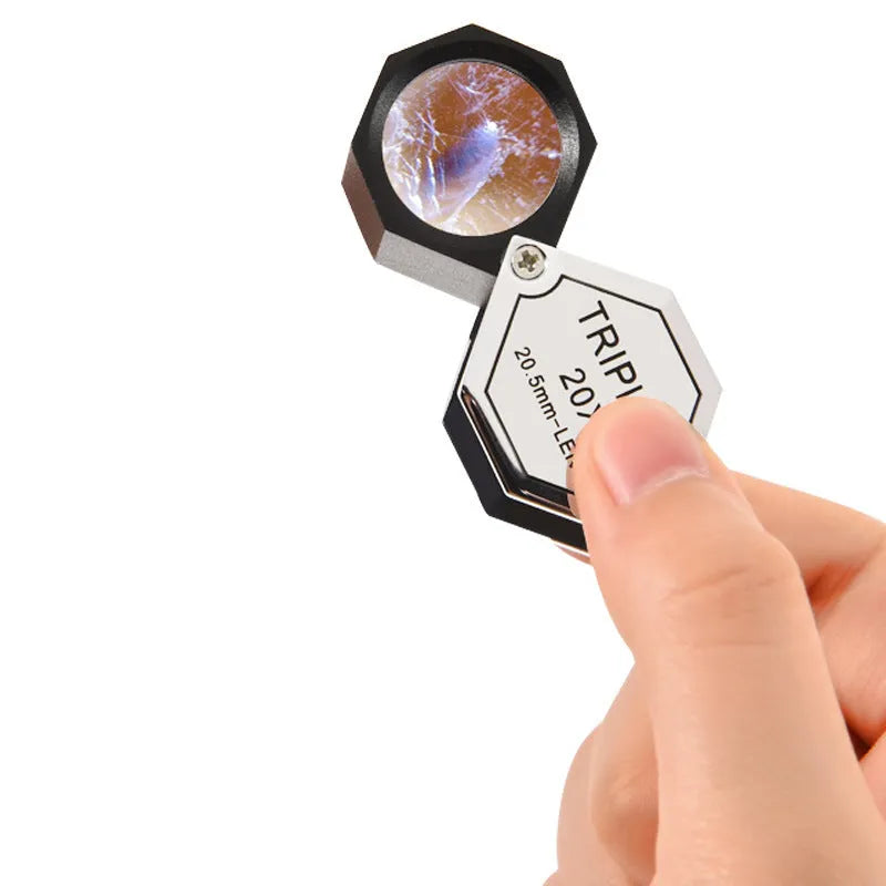 Handheld metal jeweller's loupe with optical glass lens for stamp and coin identification.