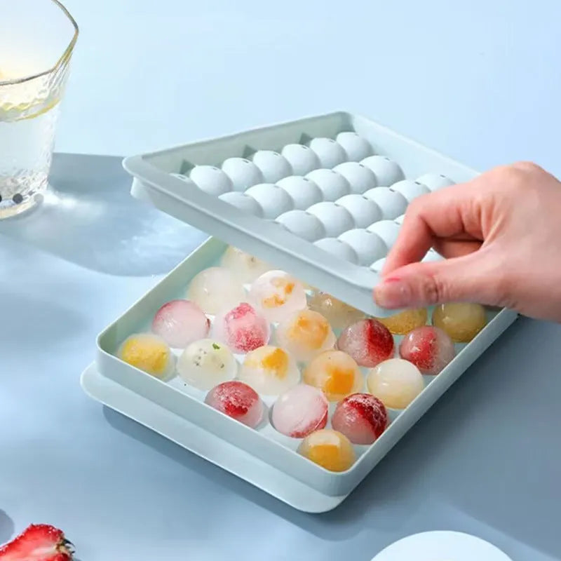 Blue round silicone ice cube tray with 33 grids and a clear lid, shown next to pink version