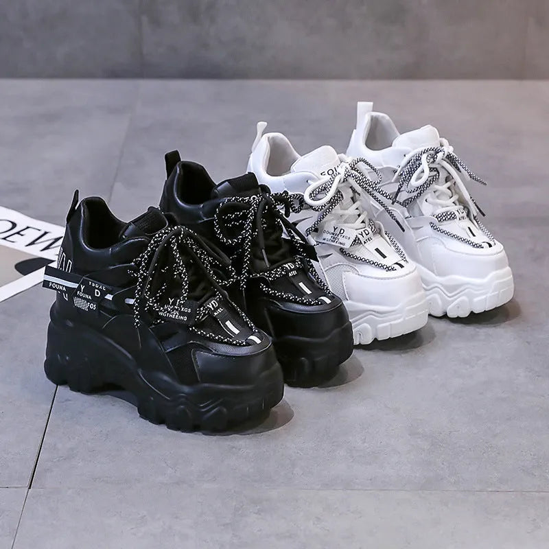 Women's white low-top platform trainers with mesh panels and a black cross-strap over the vamp.