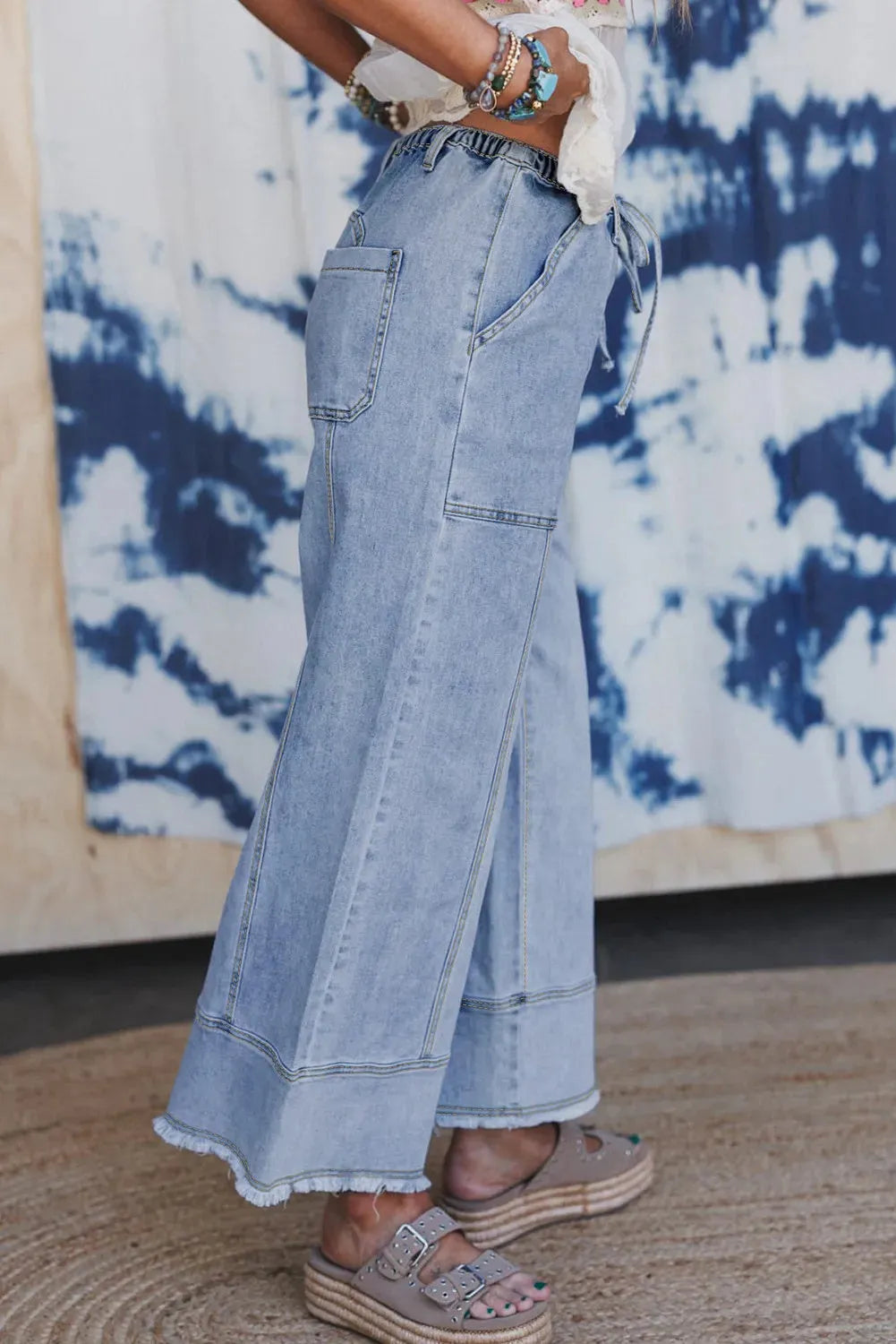 Beau blue wide leg denim trousers with a drawstring waist and raw hem detailing.