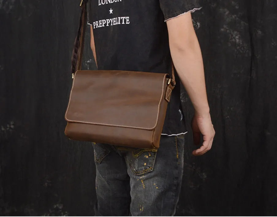 Vintage brown leather men's messenger bag with shoulder strap showing internal organiser pockets.