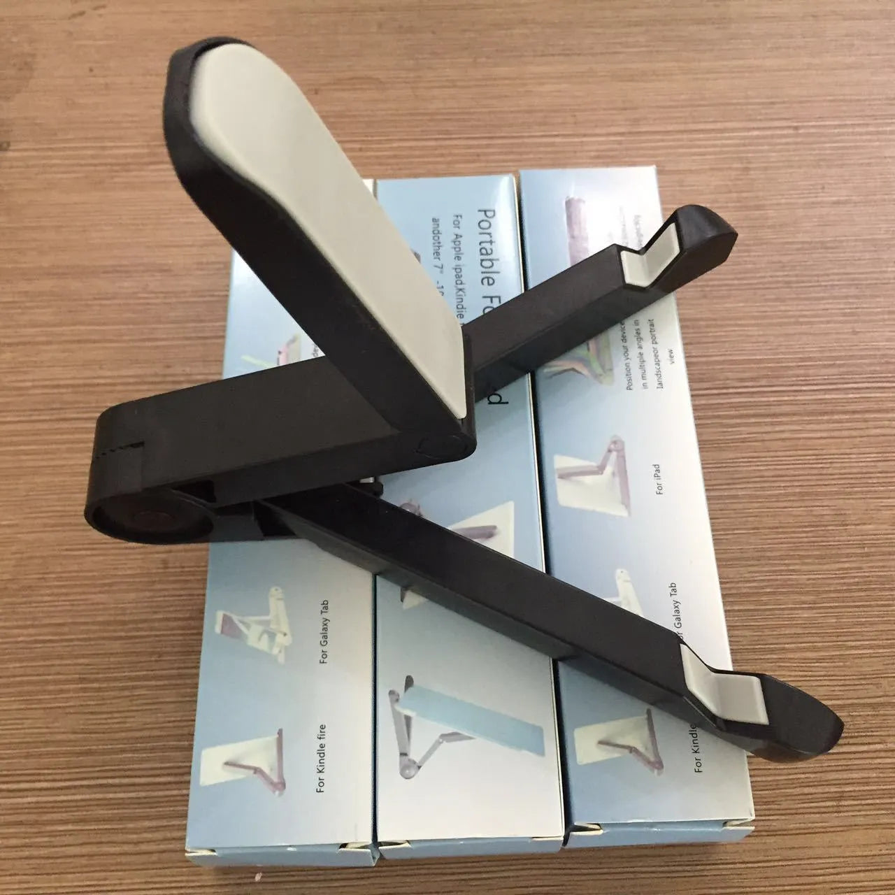 Black foldable tablet holder displaying smartphone at adjustable angle on desk