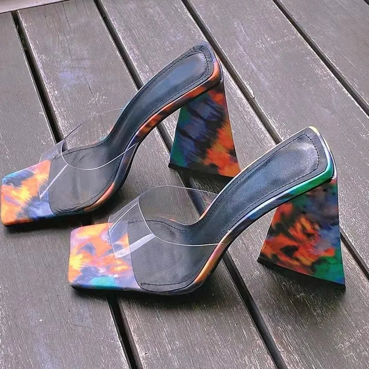 Black women's square toe slippers with a thick rubber heel on a wooden floor.