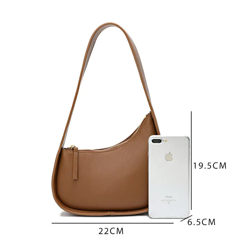 Small half-moon shaped leather ladies handbag with wide shoulder strap and zip opening
