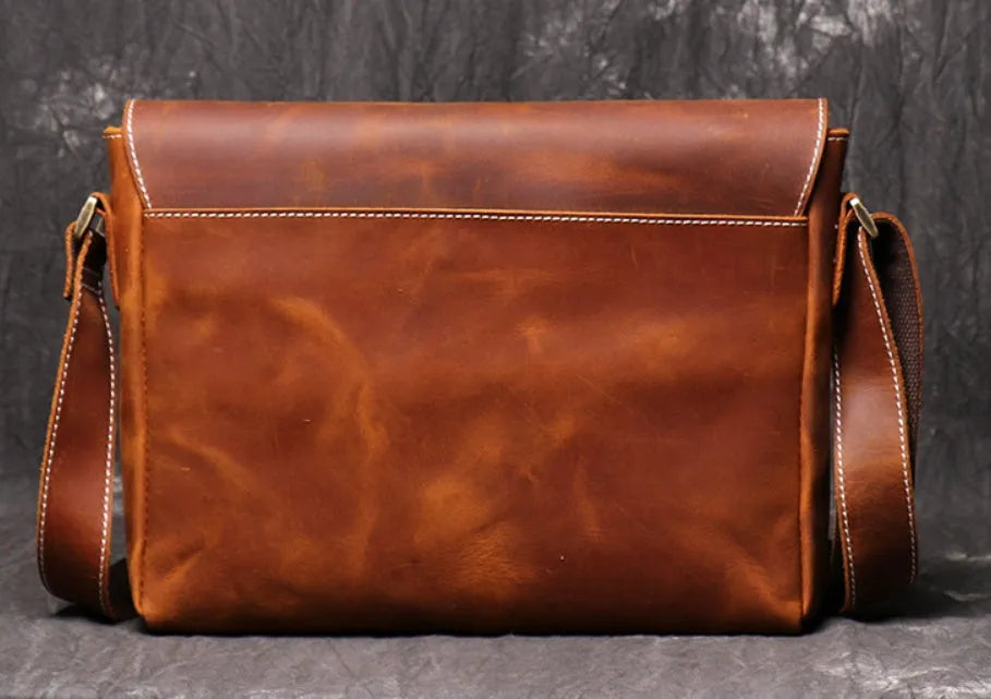 Vintage brown leather men's messenger bag with shoulder strap showing internal organiser pockets.