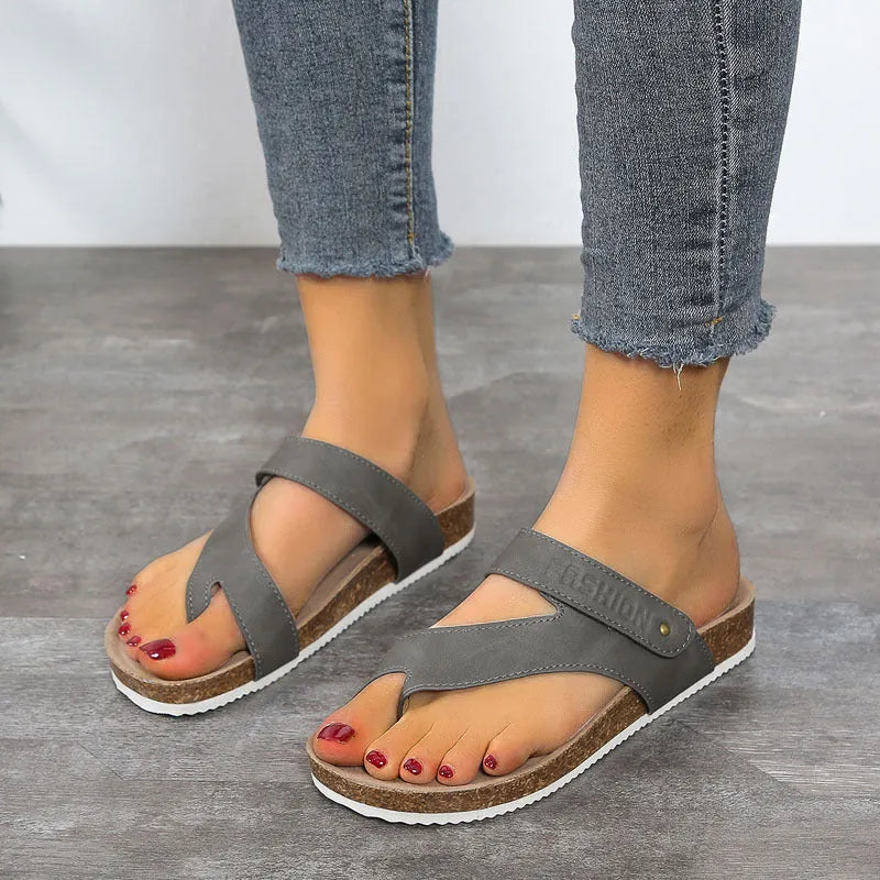 Flat toe ring flip-flops in blue with a thick foam sole on a wooden floor.
