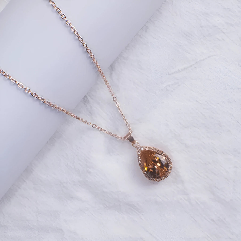 Water drop shaped pendant necklace with geometric design and rhinestone accents in pink colour