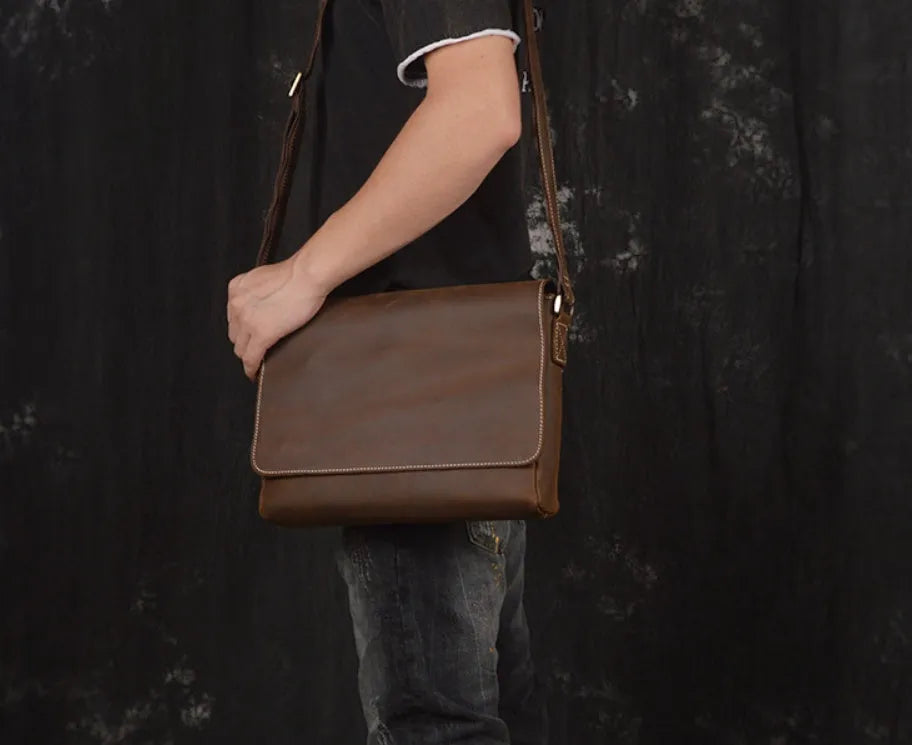 Vintage brown leather men's messenger bag with shoulder strap showing internal organiser pockets.