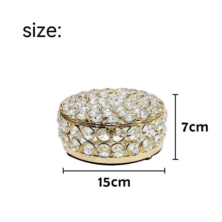 Transparent crystal glass jewelry box with a French gold metal frame on a table.