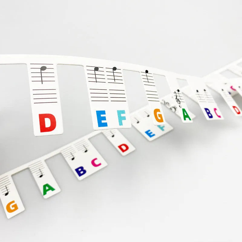 Piano keyboard note stickers on white cardboard for 88 keys, showing separate packs for black notes and colour note bars.