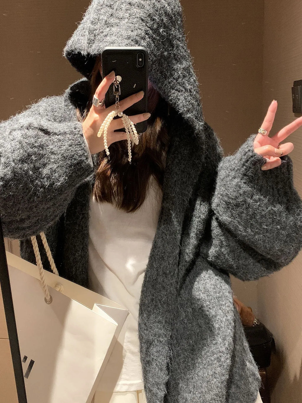 Women's retro-style thick knitted hooded cardigan in dark grey, shown open over a top.