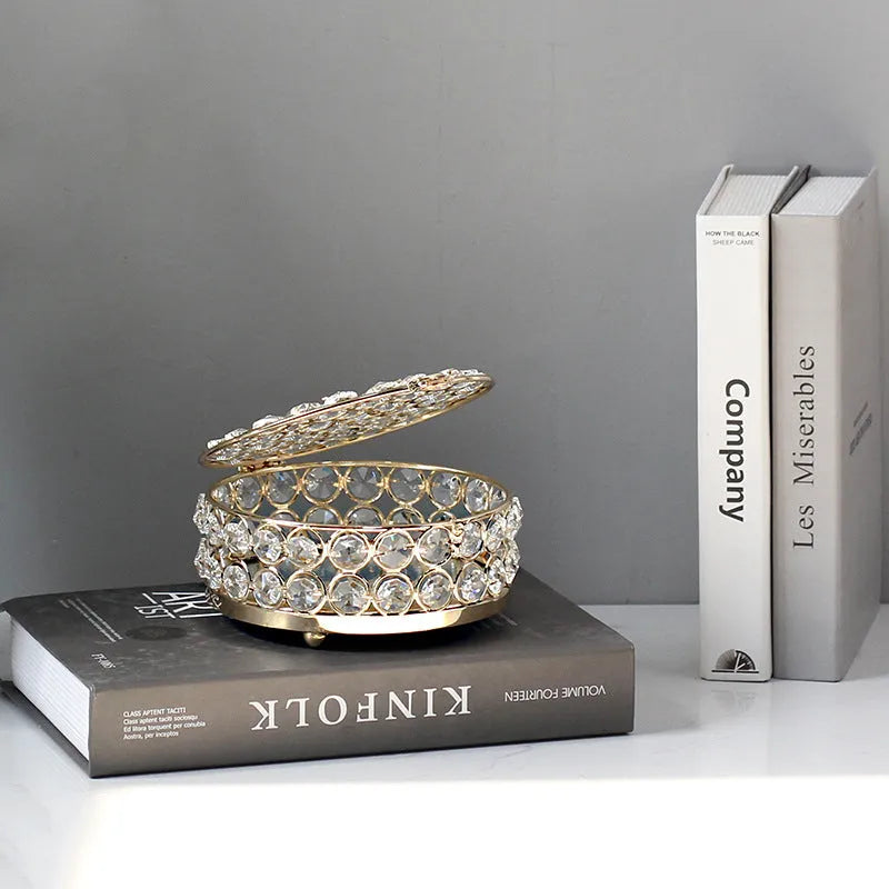 Transparent crystal glass jewelry box with a French gold metal frame on a table.