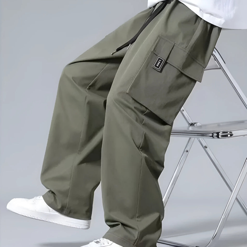 Boy wearing grey straight leg cargo pants with drawstring waist and large side pockets.