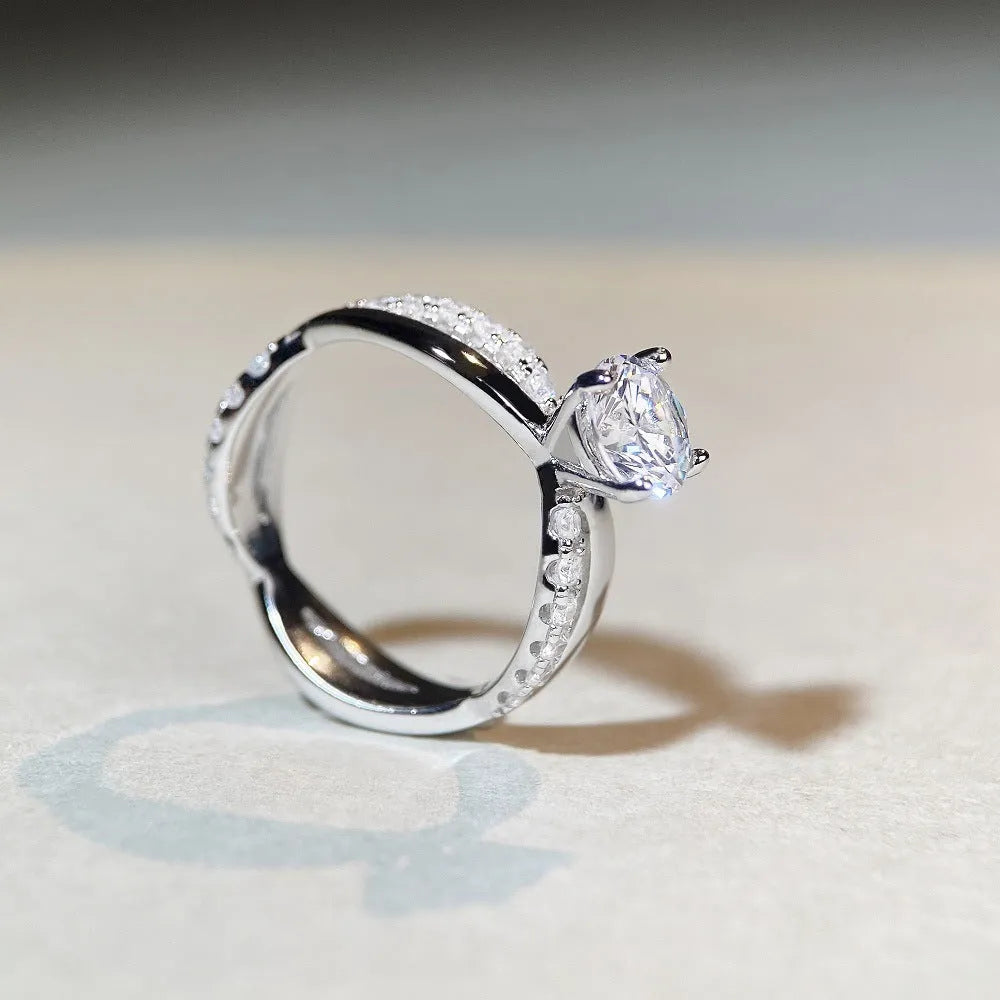Close-up of a twisted sterling silver band moissanite ring with a four-claw setting and geometric lines.