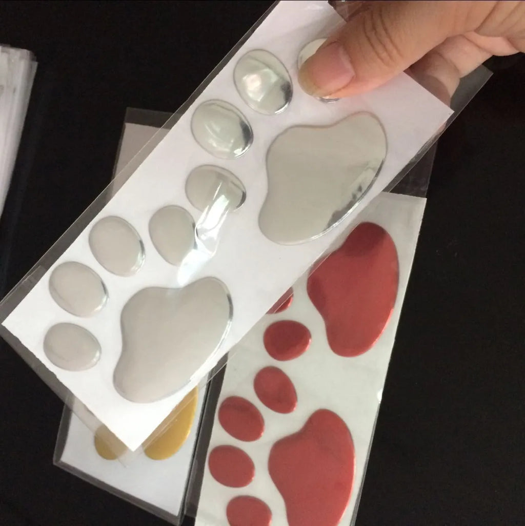 Pair of hand-shaped brush stroke car stickers with dog footprint details on a vehicle bumper.