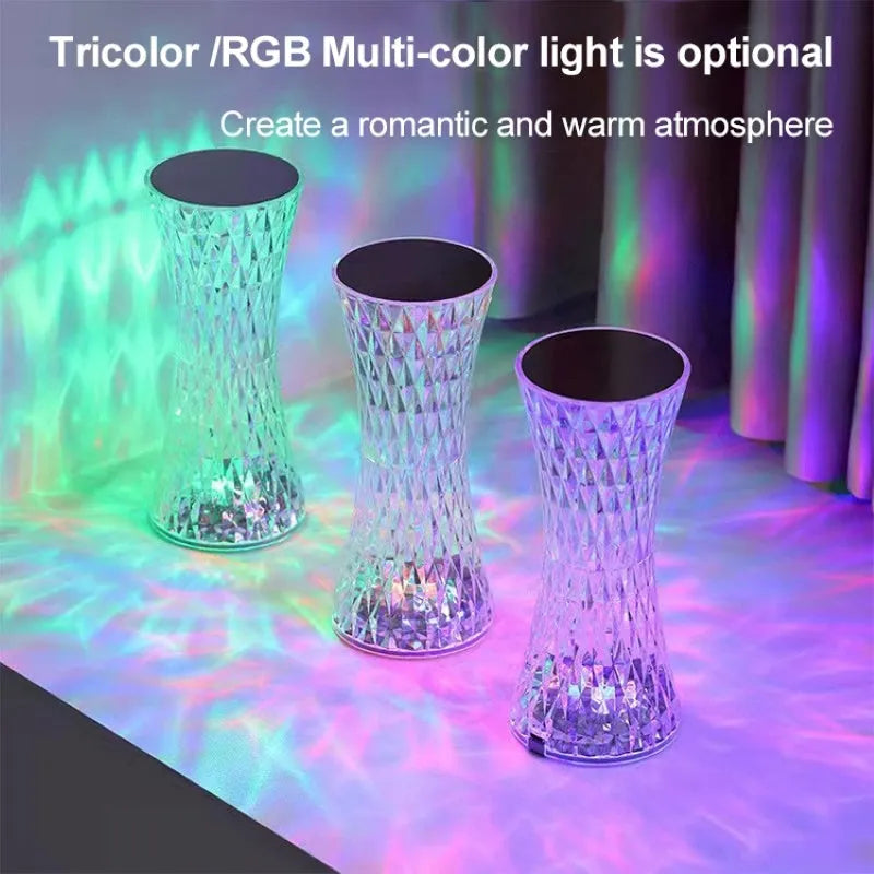 Transparent vase-shaped crystal LED table lamp with multi-colour lights on a wooden table.