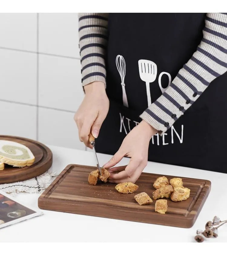 Black walnut wood cutting board with juice groove and side handle, shown in round and rectangular sizes.