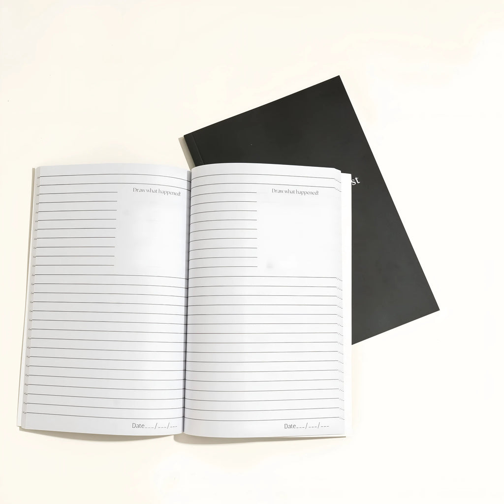 Black hardcover A5 dot grid Dream Journal notebook open on a dot grid cream paper page.