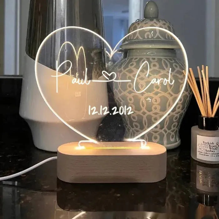 Personalised acrylic night light showing illuminated custom names and date on a transparent panel.