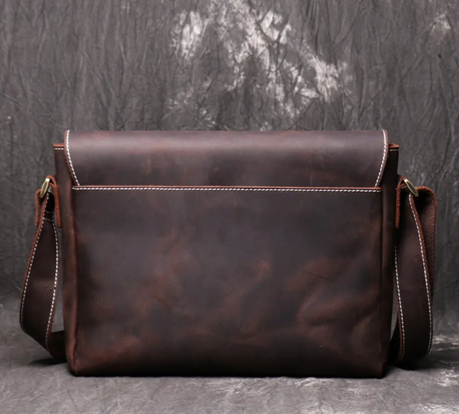 Vintage brown leather men's messenger bag with shoulder strap showing internal organiser pockets.