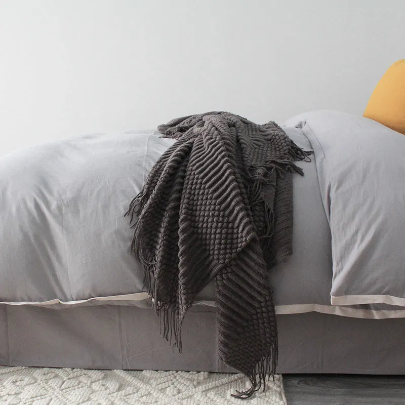 Small light grey polyester blanket folded on a sofa