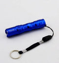 Small black aluminium LED mini flashlight with strong beam, shown next to a AA battery for scale.
