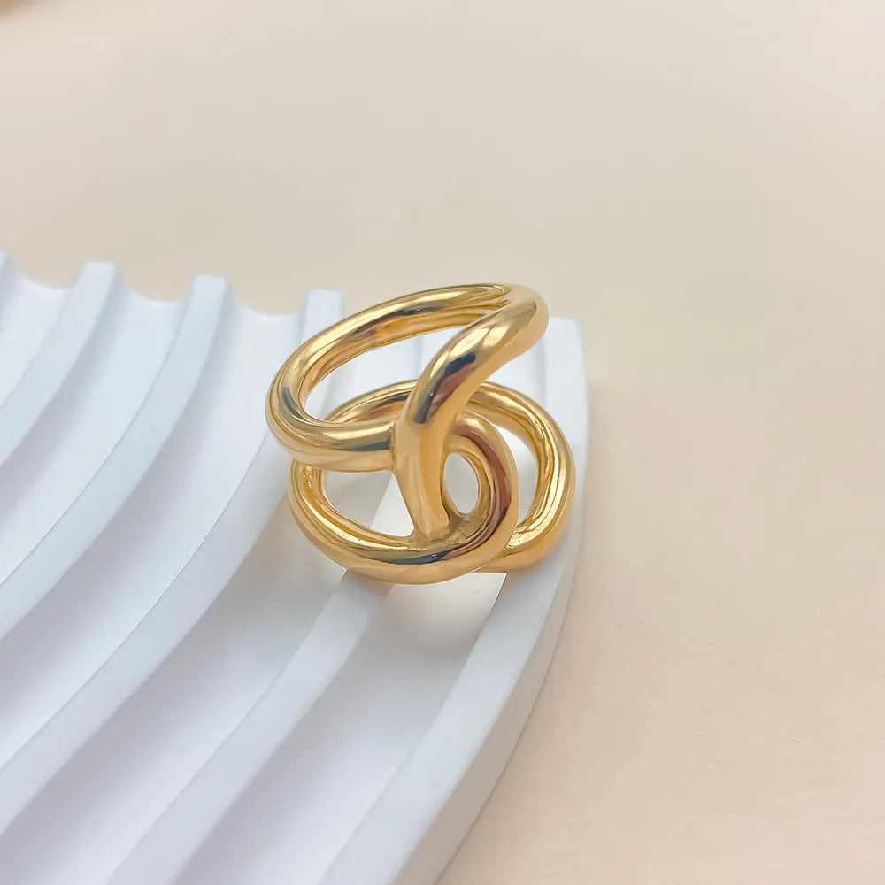 Geometric knotted U-shaped adjustable ring in stainless steel, shown in gold tone and steel colour.