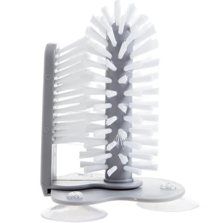 Grey 2 in 1 cup scrubber with double-sided bristles and three suction cups on the base for cleaning glassware.